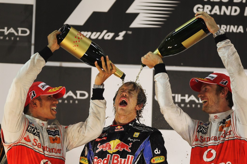 Vettel celebrates on the podium with Hamilton and Button after being crowned the 2010 world champion